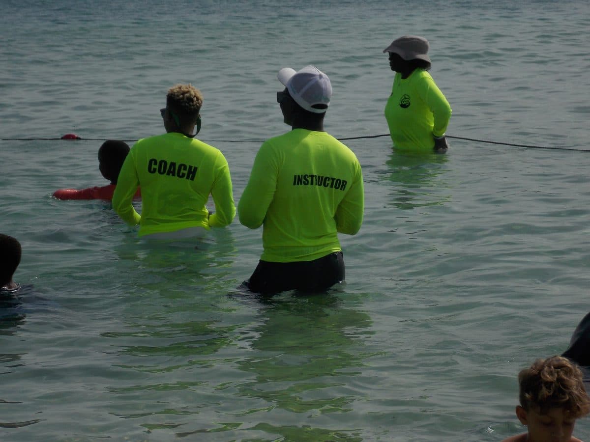 Don Shark Aquatics instructors in COACH and INSTRUCTOR rash guards leading a group coaching session in the water, Barbados